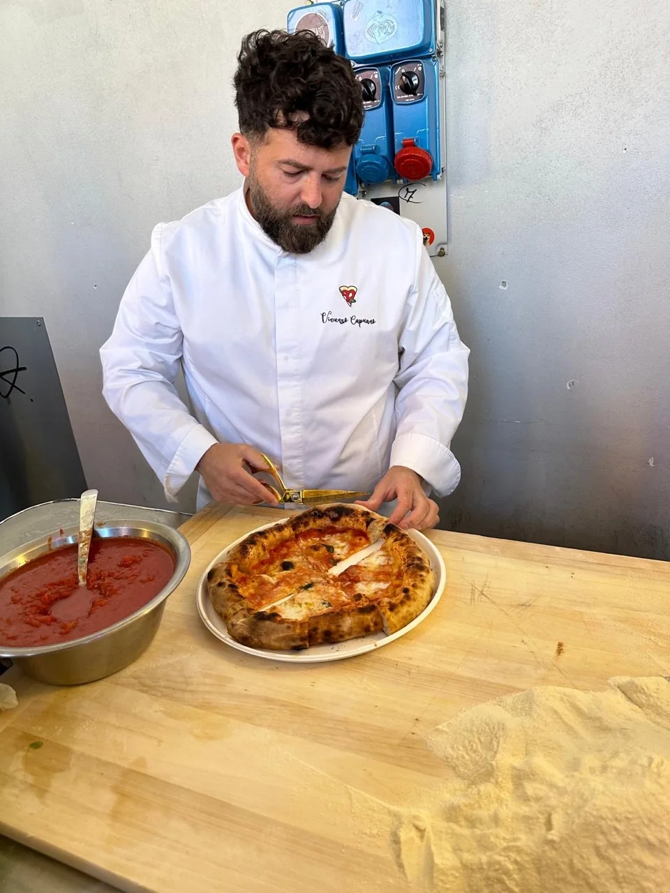 Il pizzaiolo taglia una pizza durante il corso di formazione.