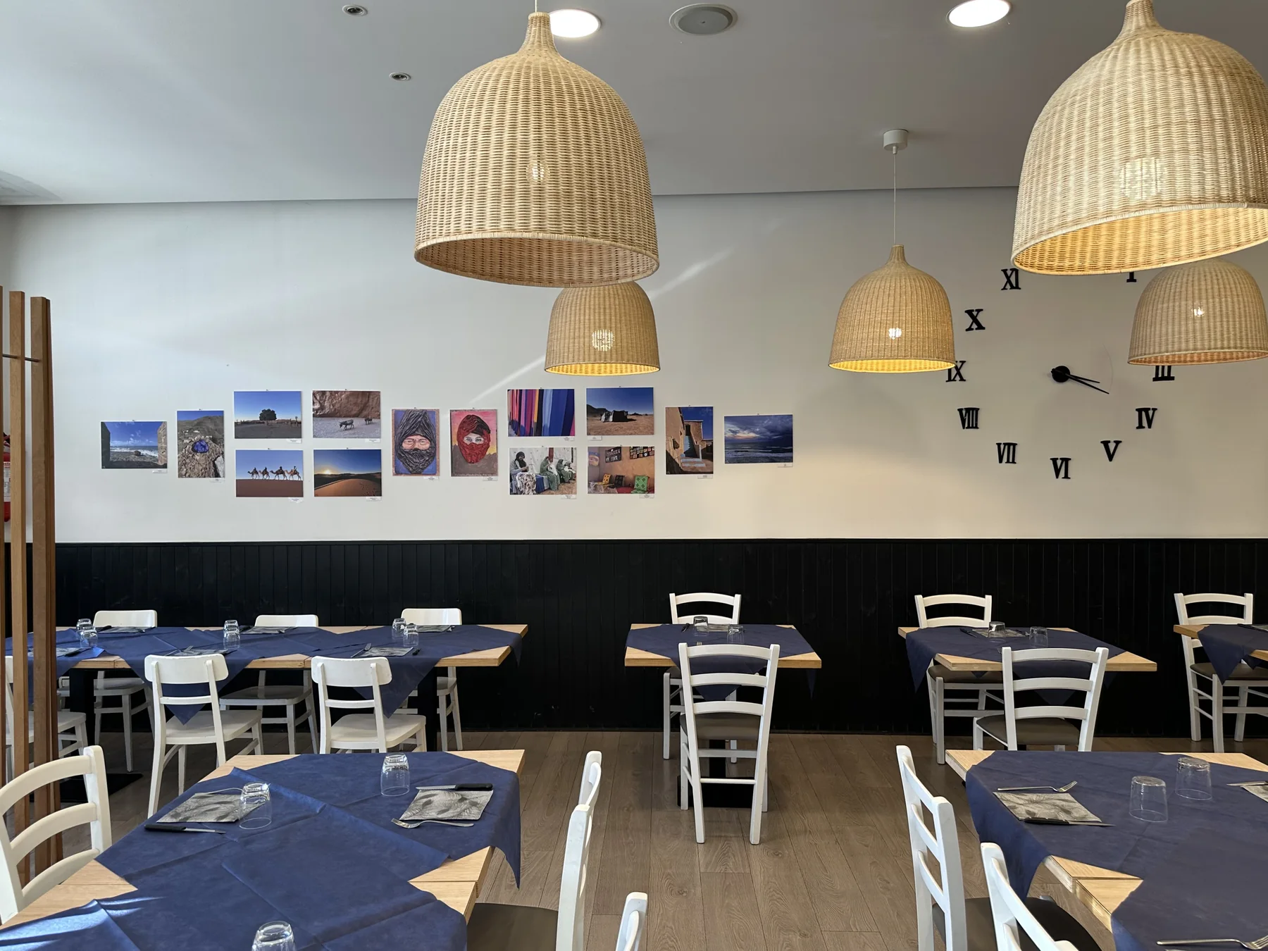 Tavoli della sala interna sotto le lampade in vimini, con decorazioni alle pareti.